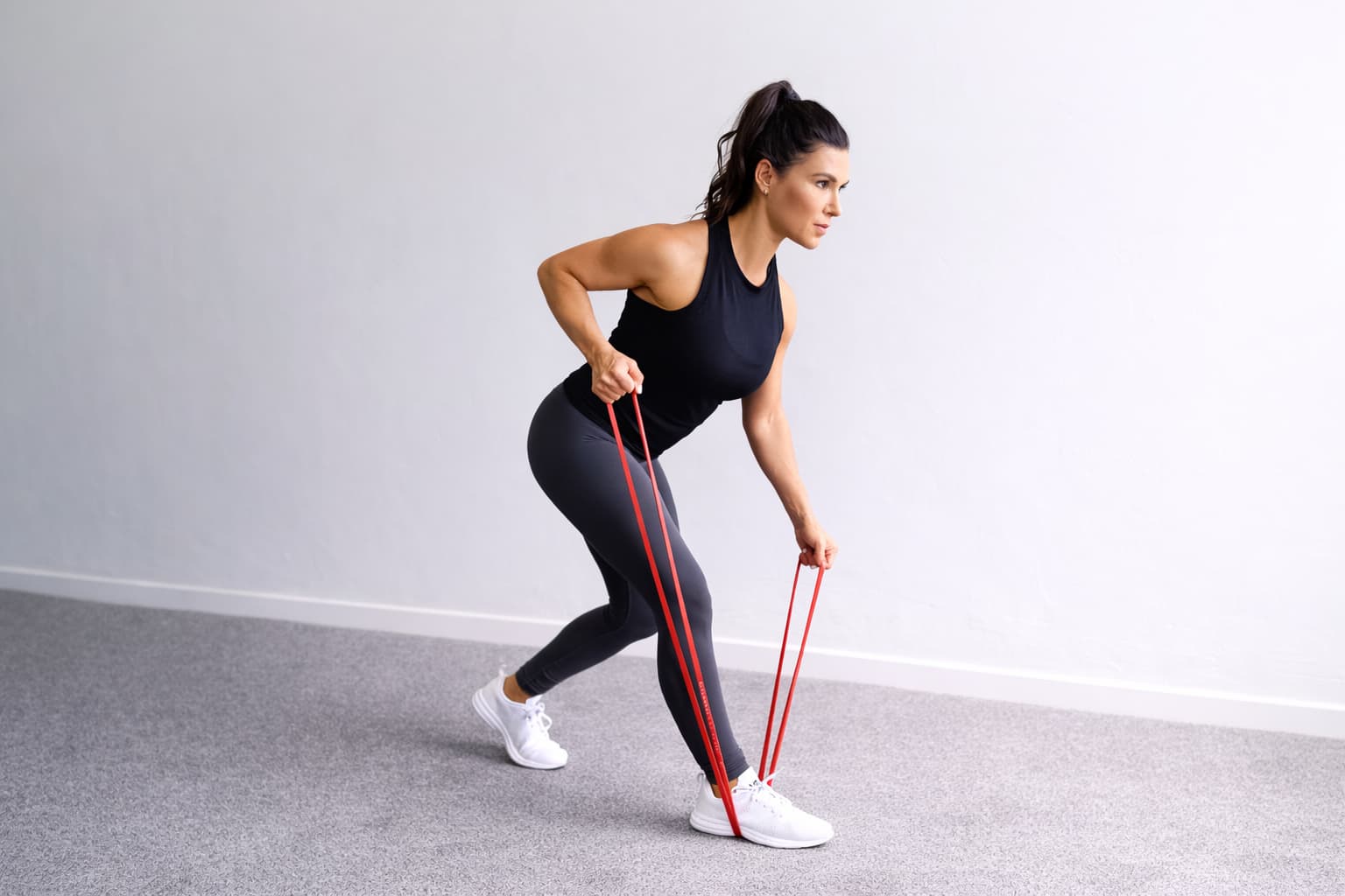 Woman performing a resistance band bent over row at home, anchoring the band under her foot