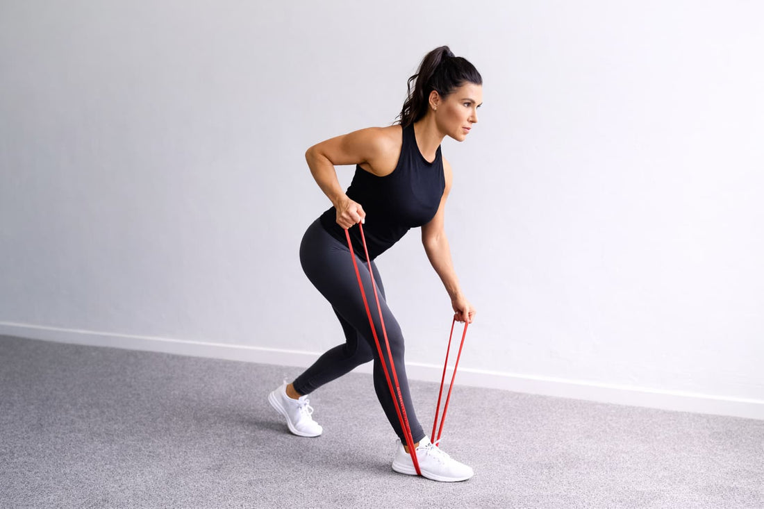 Woman performing a resistance band bent over row at home, anchoring the band under her foot